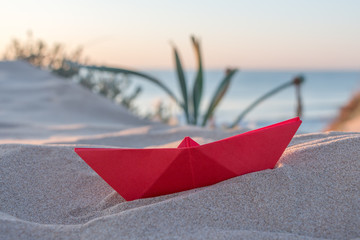 Red paper boat on a beach