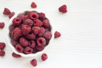 Plate with raspberries on a white wooden table