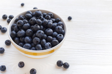 Plate with blueberries on a white wooden table