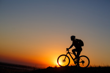 Fototapeta na wymiar Silhouette of a bike tourist on mountain peak.