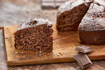 Delicious chocolate cake in white plate on wooden table background