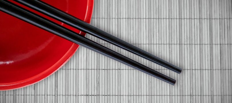 Composite image of close up of chopstick with red bowl
