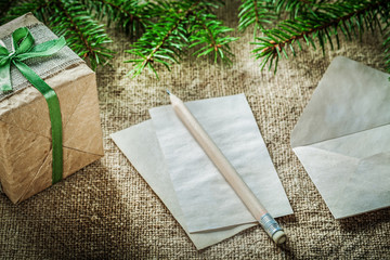 Fir tree branch handmade gift box paper pencil on sacking backgr