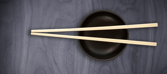 Composite image of close up of chopstick on black bowl