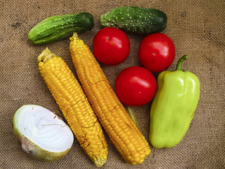 Set of vegetables on burlap.
Sweet corn,onion,red tomatos,cucumbers & green paprika