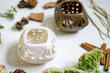 Pottery candlestick on the white wooden table. Decorative ceramics with dried flowers