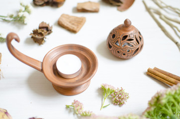 Pottery candlestick on the white wooden table. Decorative ceramics with dried flowers