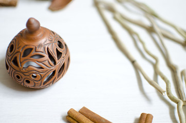 Pottery candlestick on the white wooden table. Decorative ceramics with dried flowers
