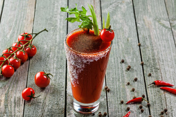 Classic bloody mary in a glass on a wooden table. Alcoholic drink made of tomato juice, vodka, pepper, salt, lemon juice, celery and other flavorings. Closeup shot. © Maxim Khytra