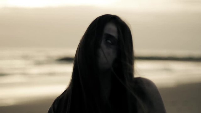 Beautiful female zombie walking on beach sad closeup