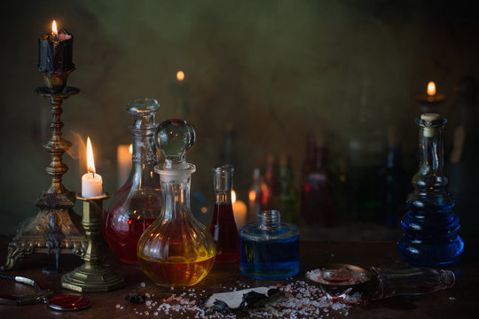 Magic potion, ancient books and candles on dark background