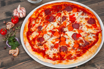 fast food. mexican pizza with pepperoni, vegetables, cheese on wood table