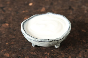 Fototapeta na wymiar Homemade sour cream in a ceramic bowl. Dark background.