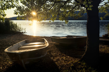 A beautiful sunset on the lake of Pusiano with two row boats docked in the foreground, Lecco, Italy