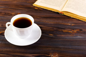 Still life with cup of coffee and book on grunge wood table in vintage style