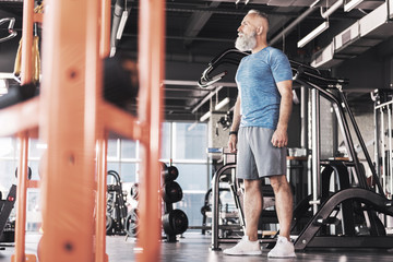 Fototapeta na wymiar Pensive old male is training in gym