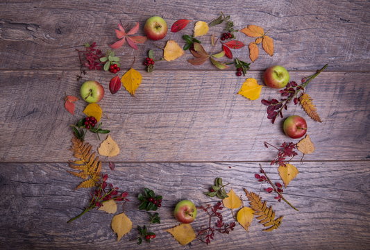 Autumn arrangement of leaves, apples and berries on a wooden background with free space for text. Top view, concept of the season