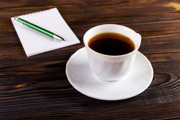 notebook with pen and coffee cup on wooden background, business concept