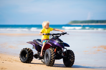Fototapeta na wymiar Child on quad bike at beach. All-terrain vehicle.