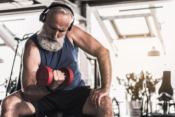 Confident old pensioner is spending time in gym