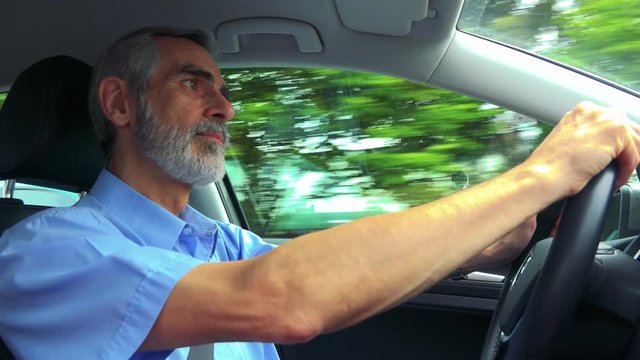 Senior man drives a car in summer day 