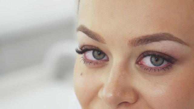 Cute young woman shifting her gaze to the camera at the beauty salon. Micro close up of beautiful female green eyes. Pretty caucasian girl demonstrating the result of beauty treatment