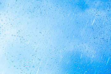 Water drops on a window glass after the rain. The sky with clouds on background.