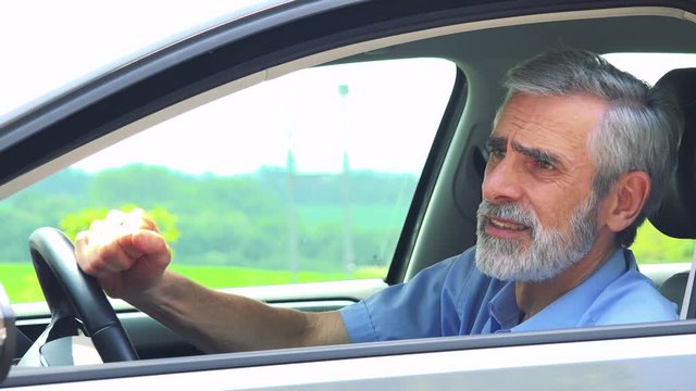 Senior man sits in the car and has depression - closeup shot from side - countryside in the background 