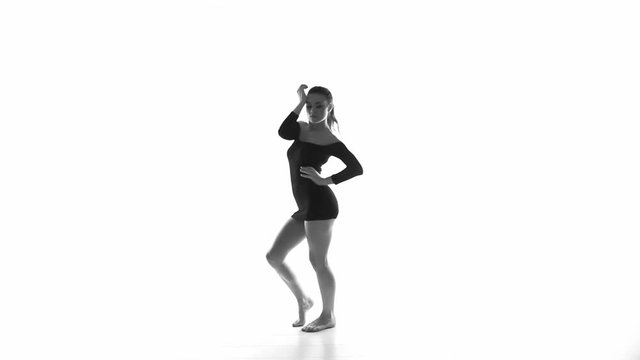Modern beautiful woman dancer in black dress dancing contemporary over white background indoors - black and white video