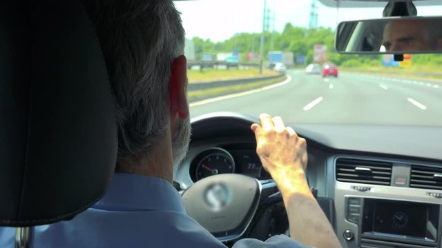 Senior man drives a car in summer day - road with many lanes 
