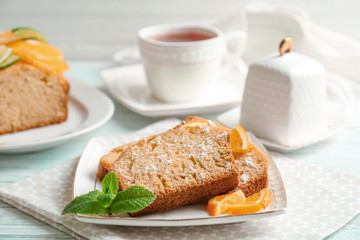 Plate with delicious sliced citrus cake and orange on table