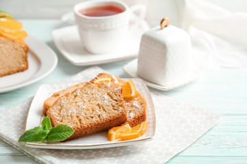 Plate with delicious sliced citrus cake and orange on table