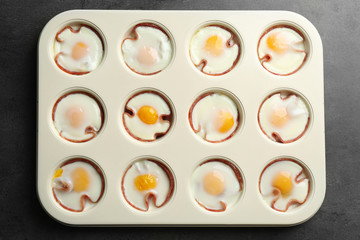 Muffin tin with tasty eggs and ham on table