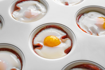 Muffin tin with tasty eggs and ham, closeup
