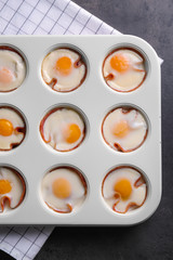 Muffin tin with tasty eggs and ham on table