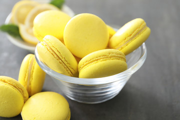 Glass bowl with tasty homemade lemon macarons on table