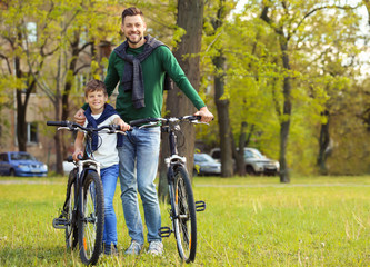 Fototapeta na wymiar Dad and son standing with their bicycles outdoors