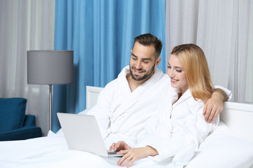 Young couple using laptop in hotel room