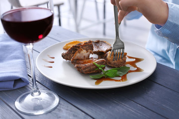 Young woman eating delicious ribs in restaurant