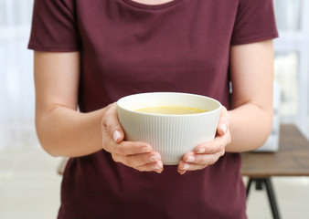 Woman holding bowl with tasty soup in kitchen
