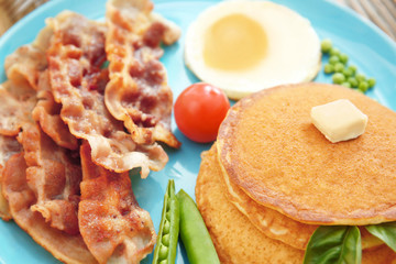 Tasty breakfast with fried egg, pancakes and bacon, close up