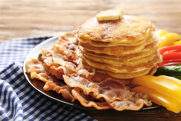 Tasty breakfast with pancakes, bacon and vegetables