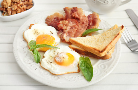 Tasty breakfast with fried eggs and bacon on table
