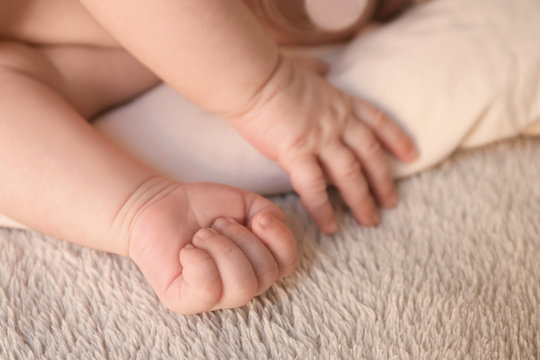Hands of cute little baby lying on bed at home