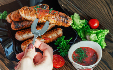 Woman's hands holding barbeque fork with grilled sausage
