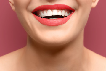 Young woman with healthy teeth laughing on colour background, closeup