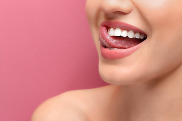 Young smiling woman licking her teeth on colour background, closeup - obrazy, fototapety, plakaty