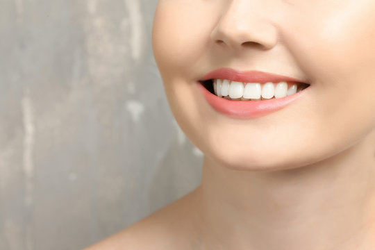 Young woman with healthy teeth on grey background
