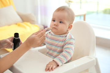 Mother giving medicine for baby indoors