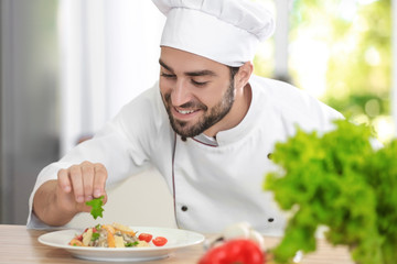 Young male chef garnishing his dish in kitchen